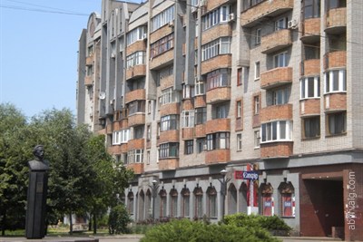 Памятник на фоне дома.