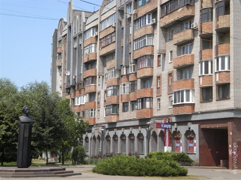 Памятник на фоне дома.